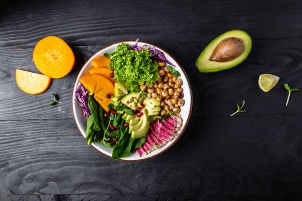 A colorful healthy salad bowl with fresh vegetables on a bright white table